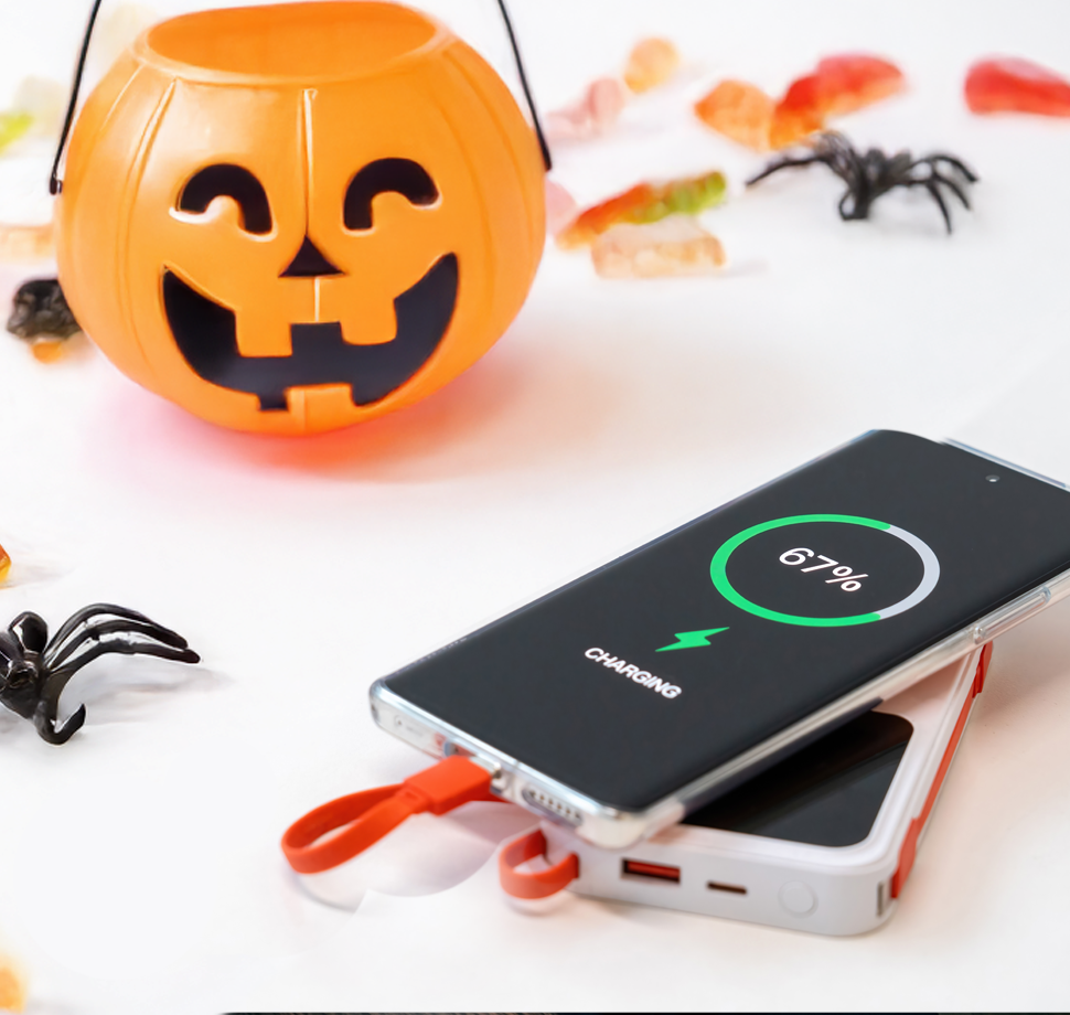 Ein Smartphone wird mit einer Powerbank aufgeladen, damit es die ganze Halloween-Nacht durchhält.