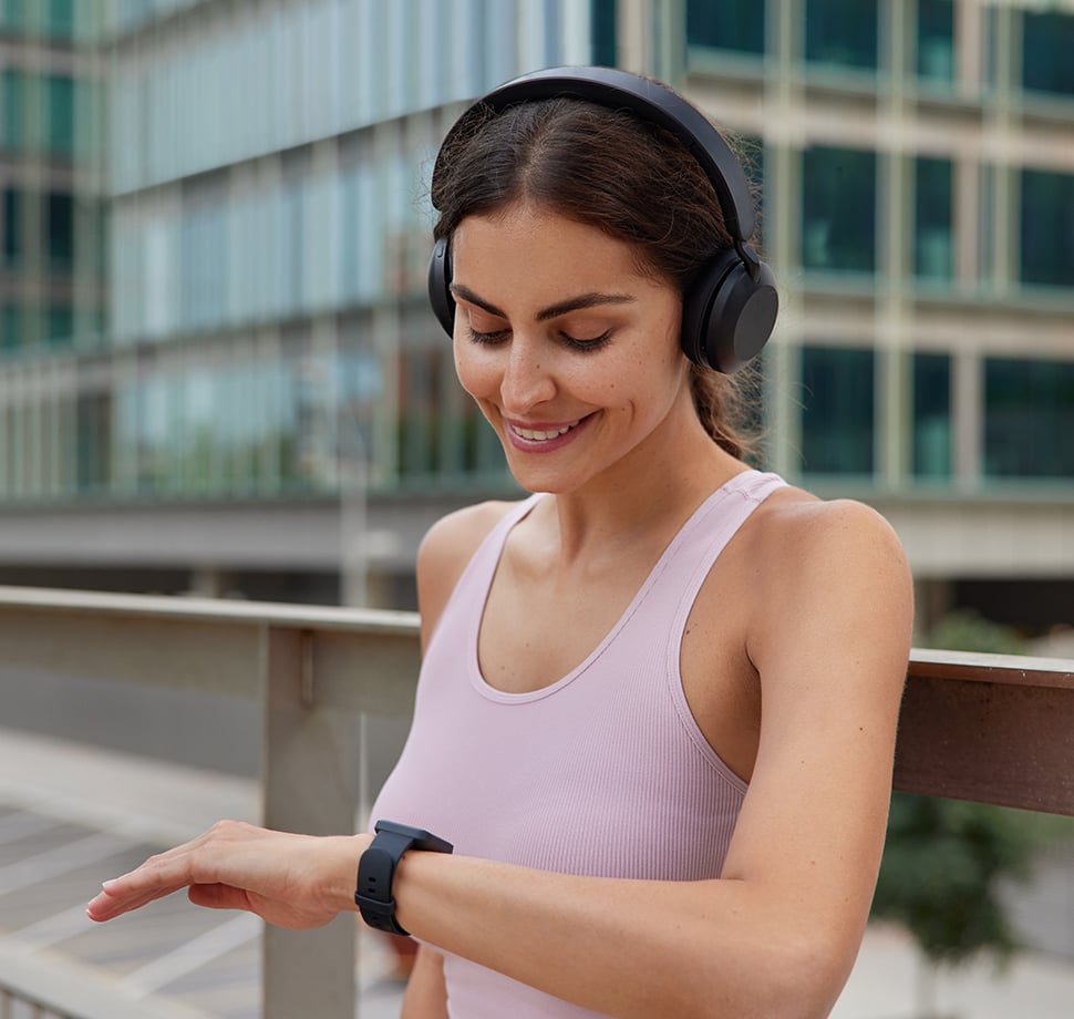 Frau mit Smartwatch und Kopfhörern organisiert ihren Alltag unterwegs – smarte Muttertags-Geschenke 2026 und praktische Geschenkideen für Mütter.