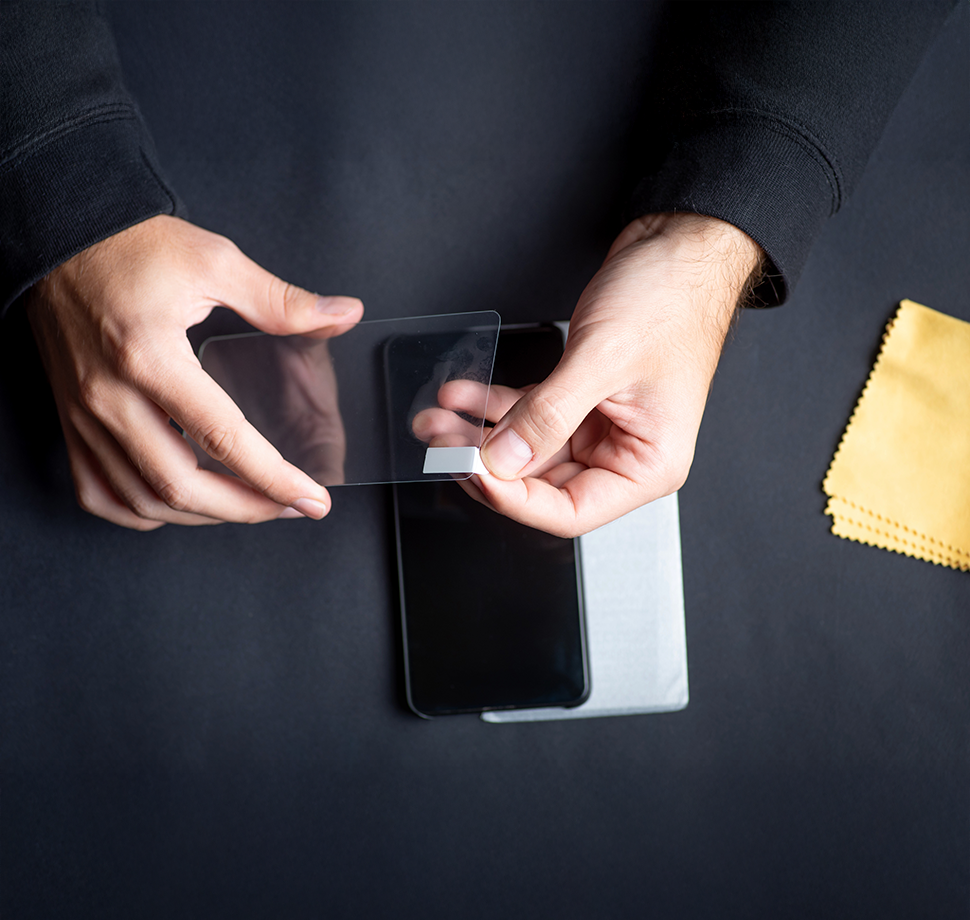 Person bringt einen neuen Displayschutz an einem Smartphone an